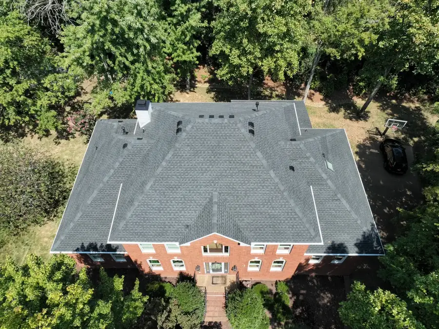 Aerial view of a repaired shingle roof surrounded by trees