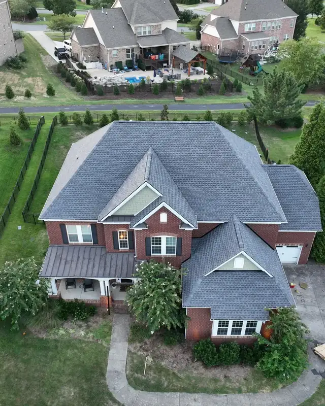 Drone view of a home with a restored roof among mature trees