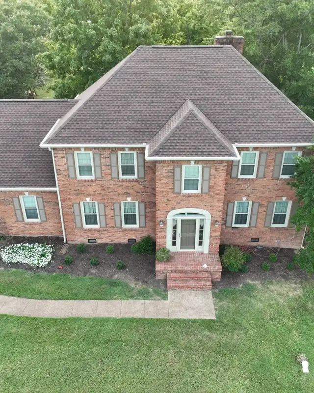 Aerial view of a brick home with a fully restored roof